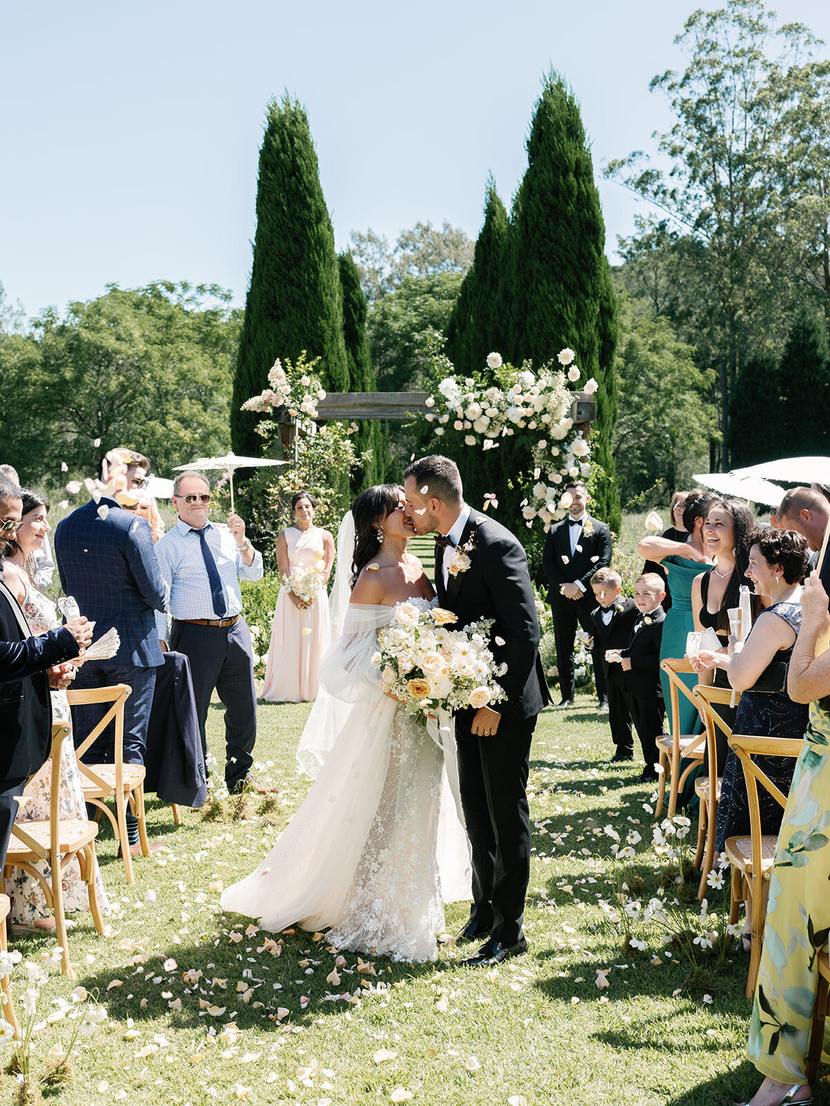 A couple kissing at the end of the aisle as guests cheer
