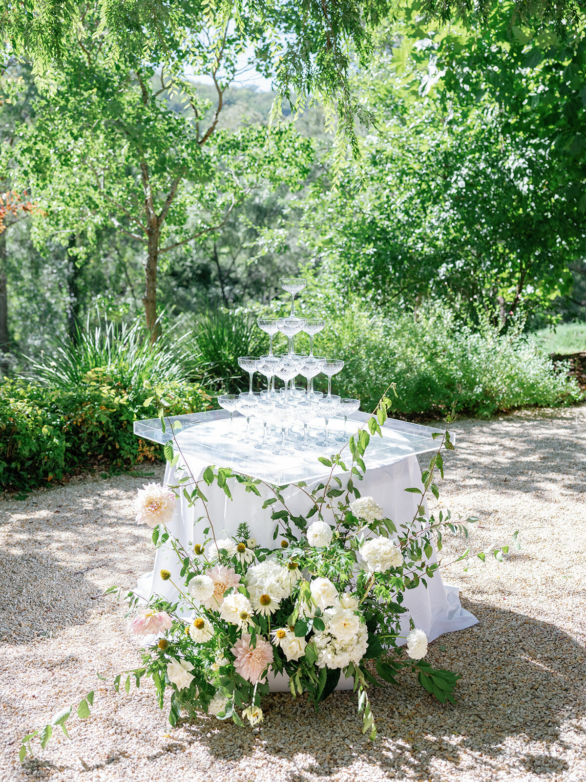 A champagne tower on a flower-covered table in a garden