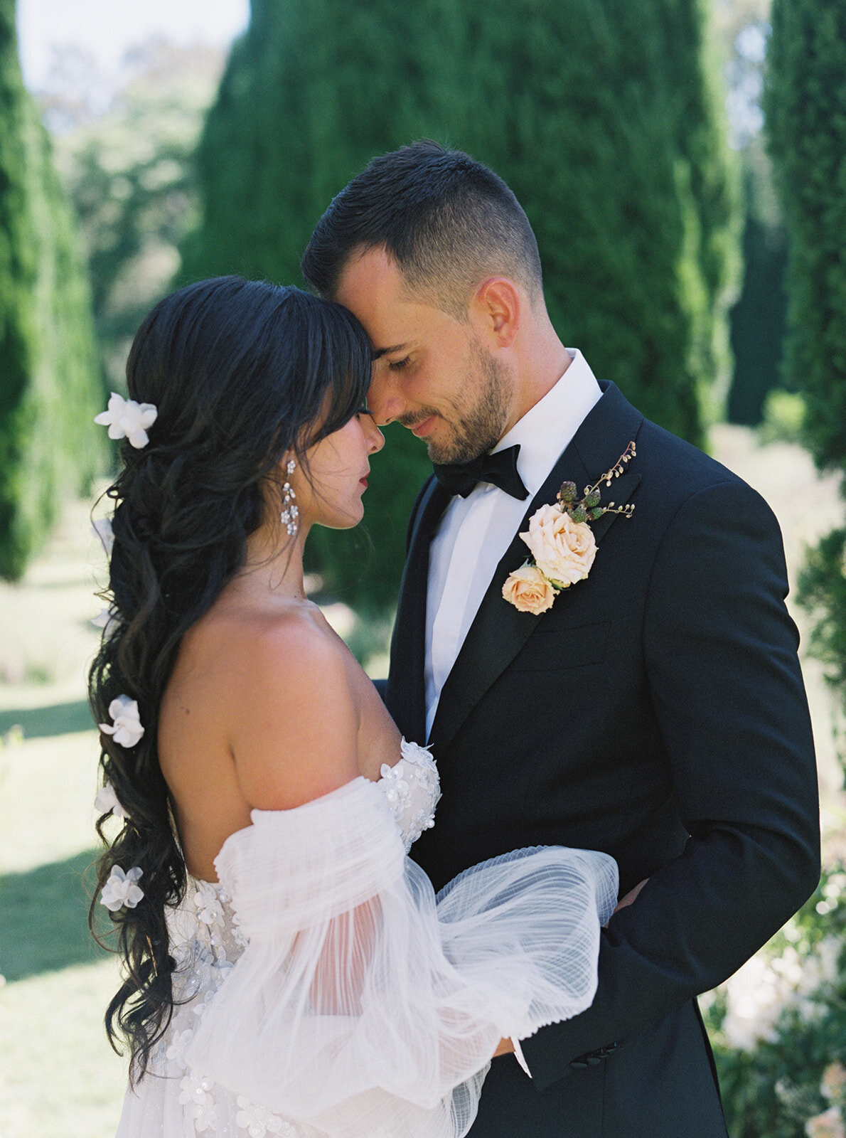 A bride and groom forehead to forehead in a garden