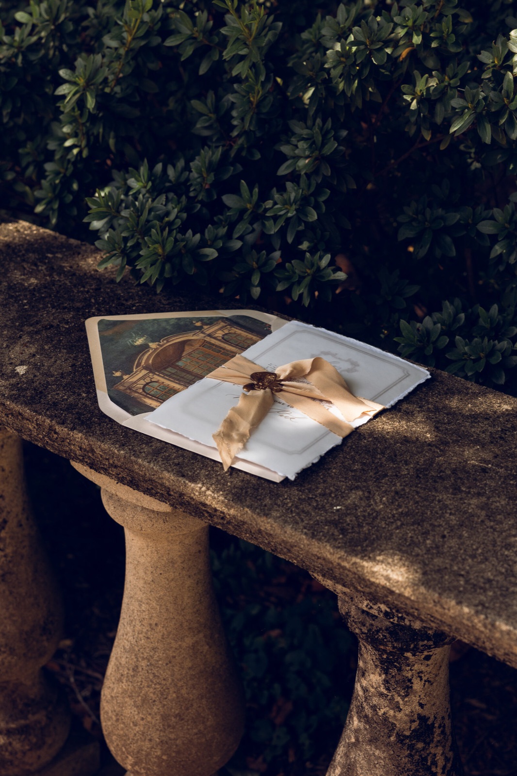A wax-sealed invitation on a stone garden bench